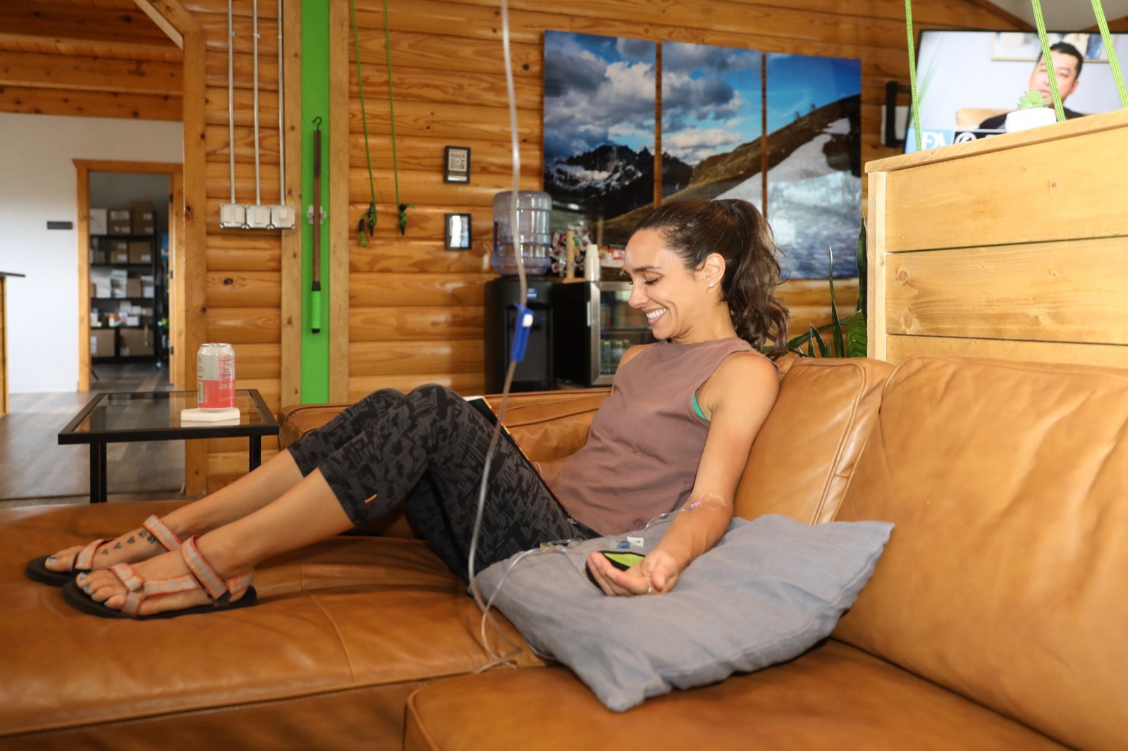 Woman smiling as she relaxes on a leather sofa during an IV therapy visit at Onus